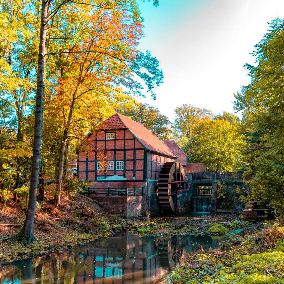 Floresta no outono e um belo e pitoresco moinho de água quebra-cabeças online