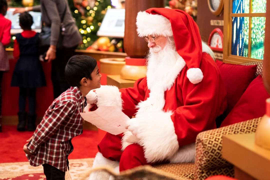 мальчик стоит перед мужчиной в костюме Санта-Клауса пазл онлайн