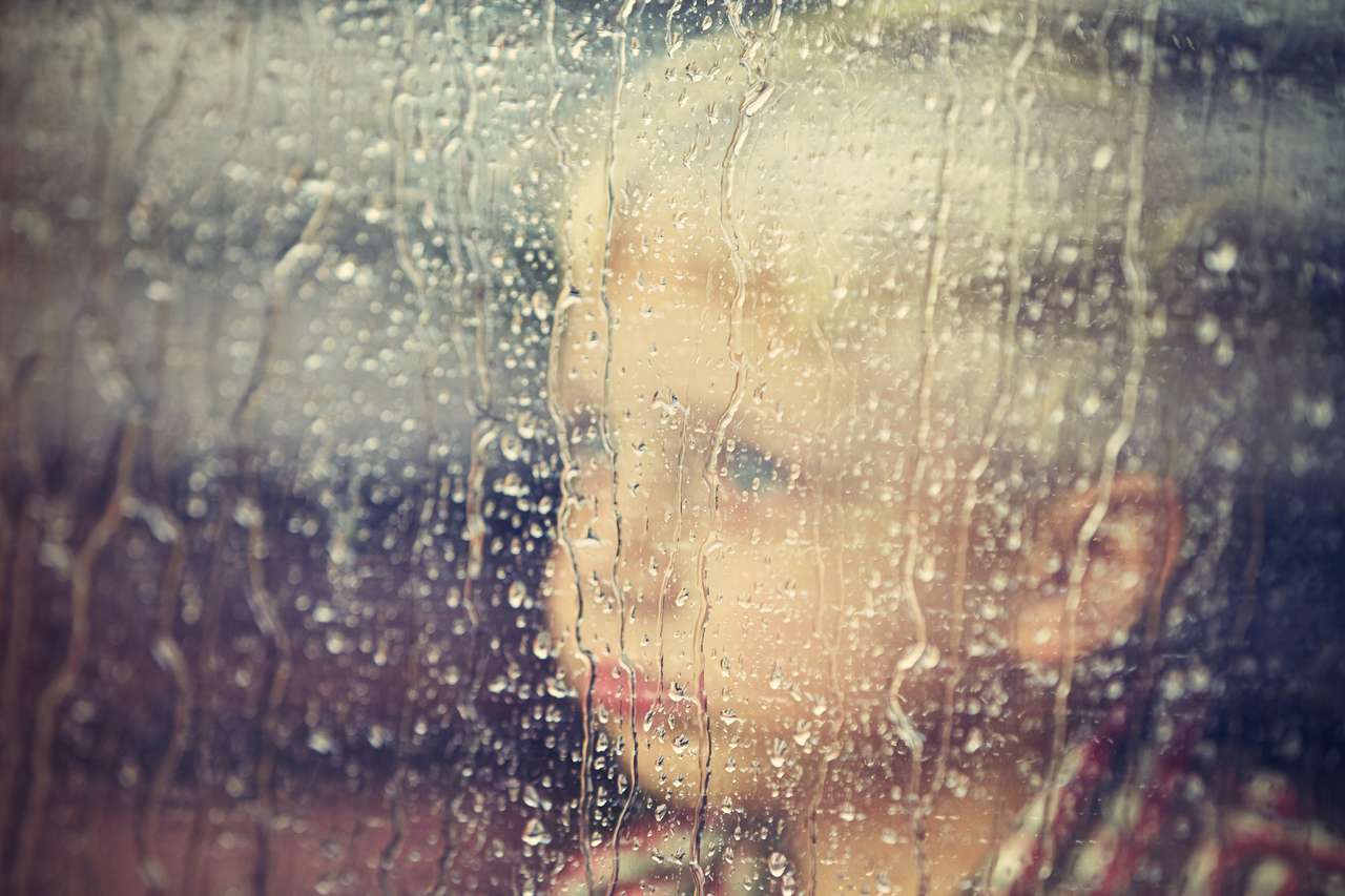 Liten pojke bakom fönstret i regnet pussel på nätet