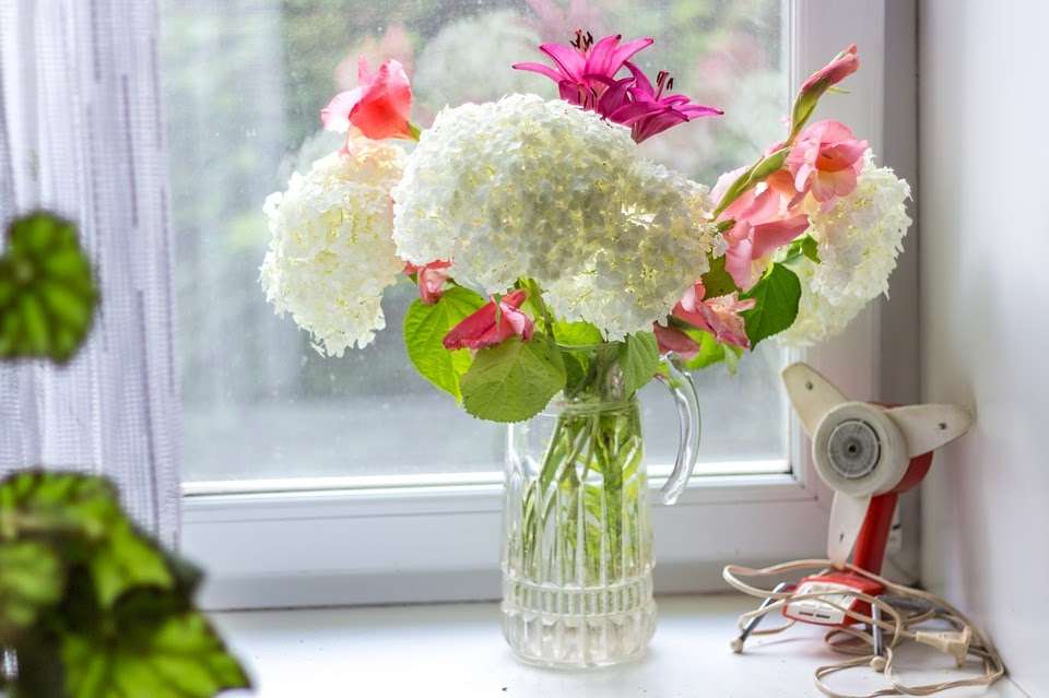Flores en una jarra en el alféizar de la ventana. rompecabezas en línea