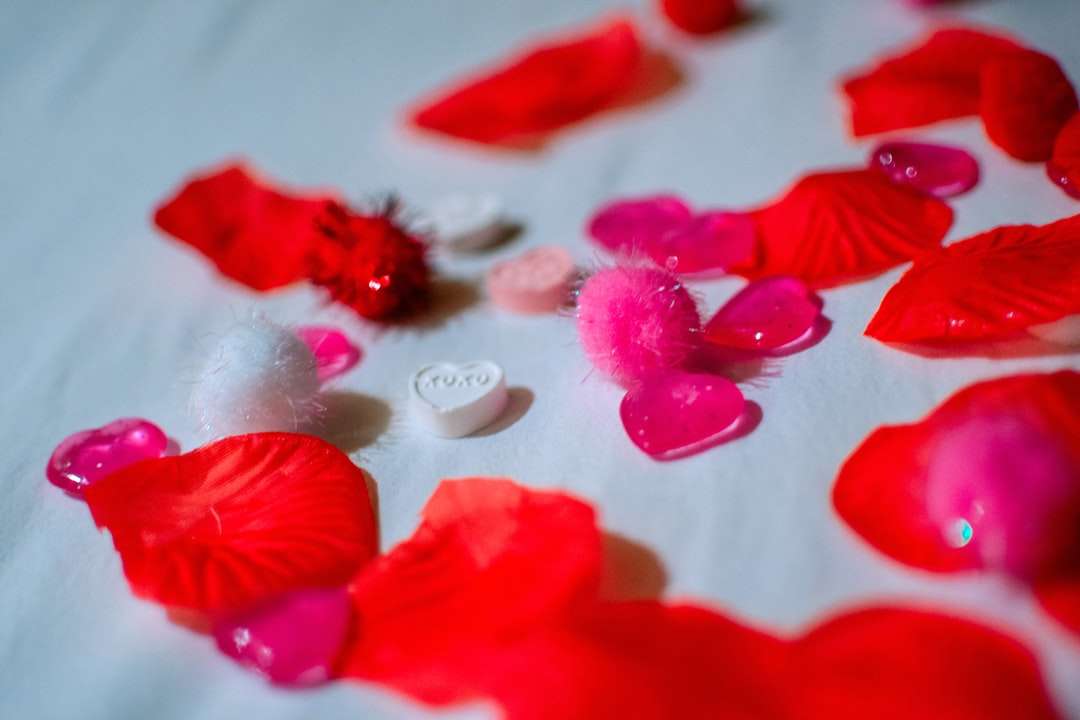 rote Blütenblätter auf weißem Textil Puzzlespiel online