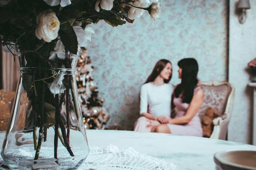 2 γυναίκα που κάθεται σε ερωτευμένο δίπλα στο τραπέζι με τριαντάφυλλο σε βάζο online παζλ