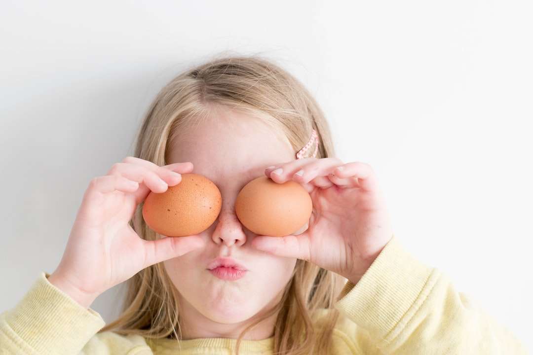 Mädchen hält zwei Eier, während sie es auf ihre Augen legt Puzzlespiel online