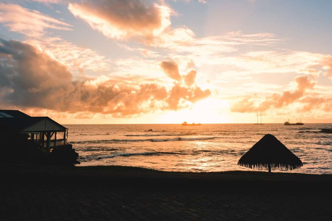 silhueta de pessoas na praia durante o pôr do sol quebra-cabeças online