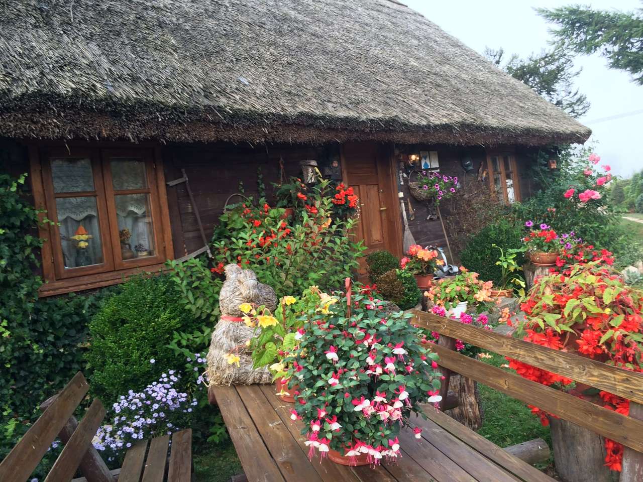 A cottage with flowers under a thatched roof jigsaw puzzle online
