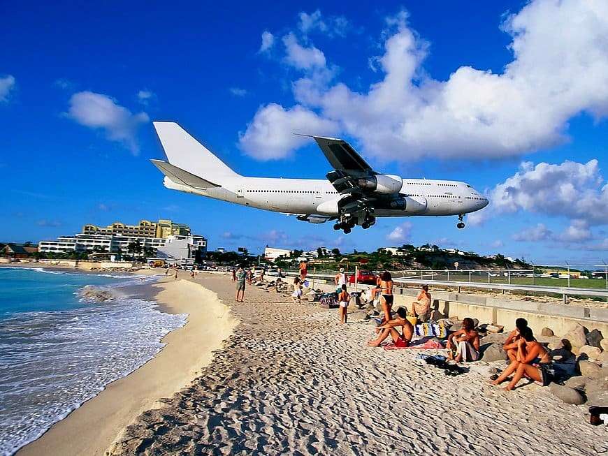 Αεροπλάνο που προσγειώνεται πάνω από την παραλία με κόσμο παζλ online