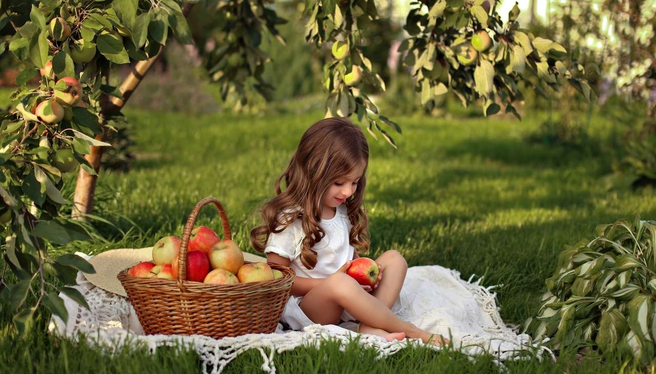 Egy lány a nyári gyümölcsösben egy almával teli kosárral kirakós online