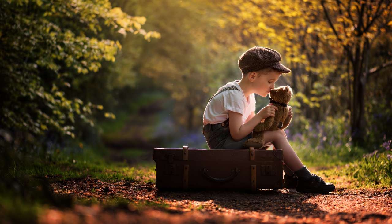 Babypojke med en nallebjörn sitter på en resväska Pussel online