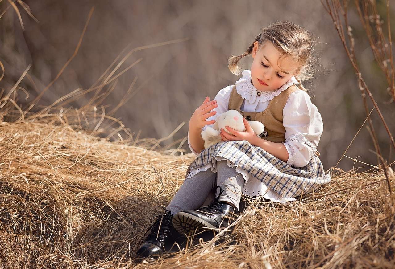 干し草の上に座っているウサギを持つ少女 オンラインパズル