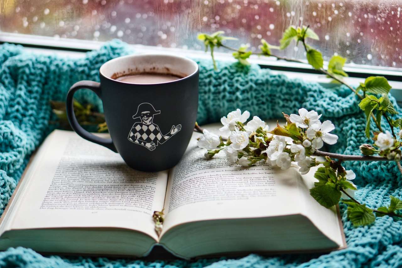 En kopp kaffe på en öppen bok en regnig dag Pussel online