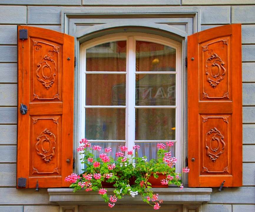 Geschnitzte Fensterläden, Blumen auf der Fensterbank. Online-Puzzle