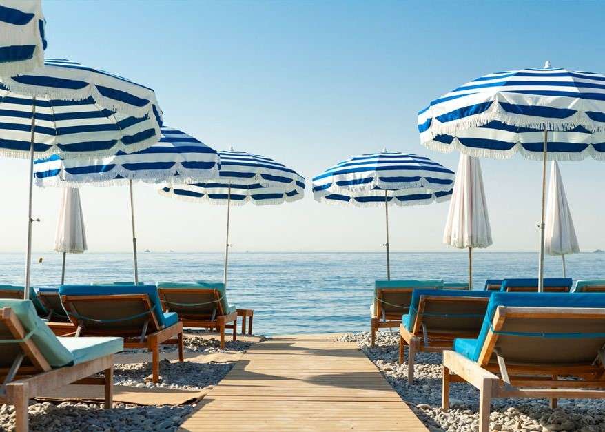 Liegestühle mit Sonnenschirmen am Meer Online-Puzzle