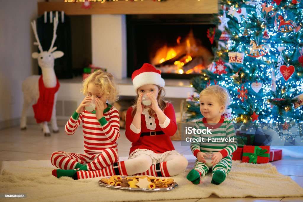 Gyermek a karácsonyfán Gyermekek a kandalló mellett karácsony estéjén online puzzle