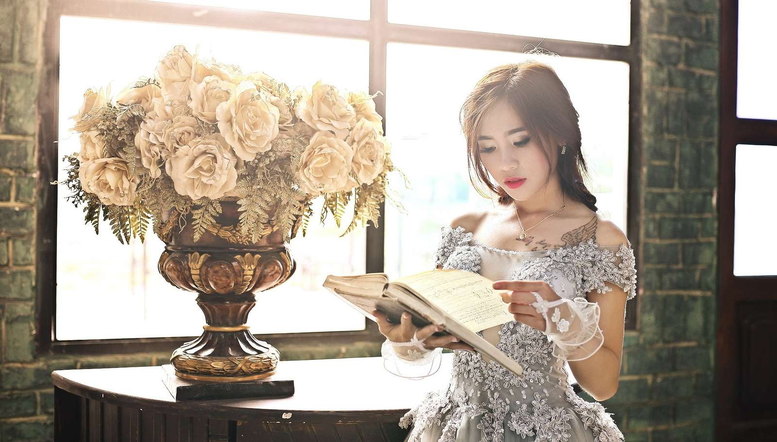 Donna con un libro accanto alle rose in un vaso vicino alla finestra puzzle online