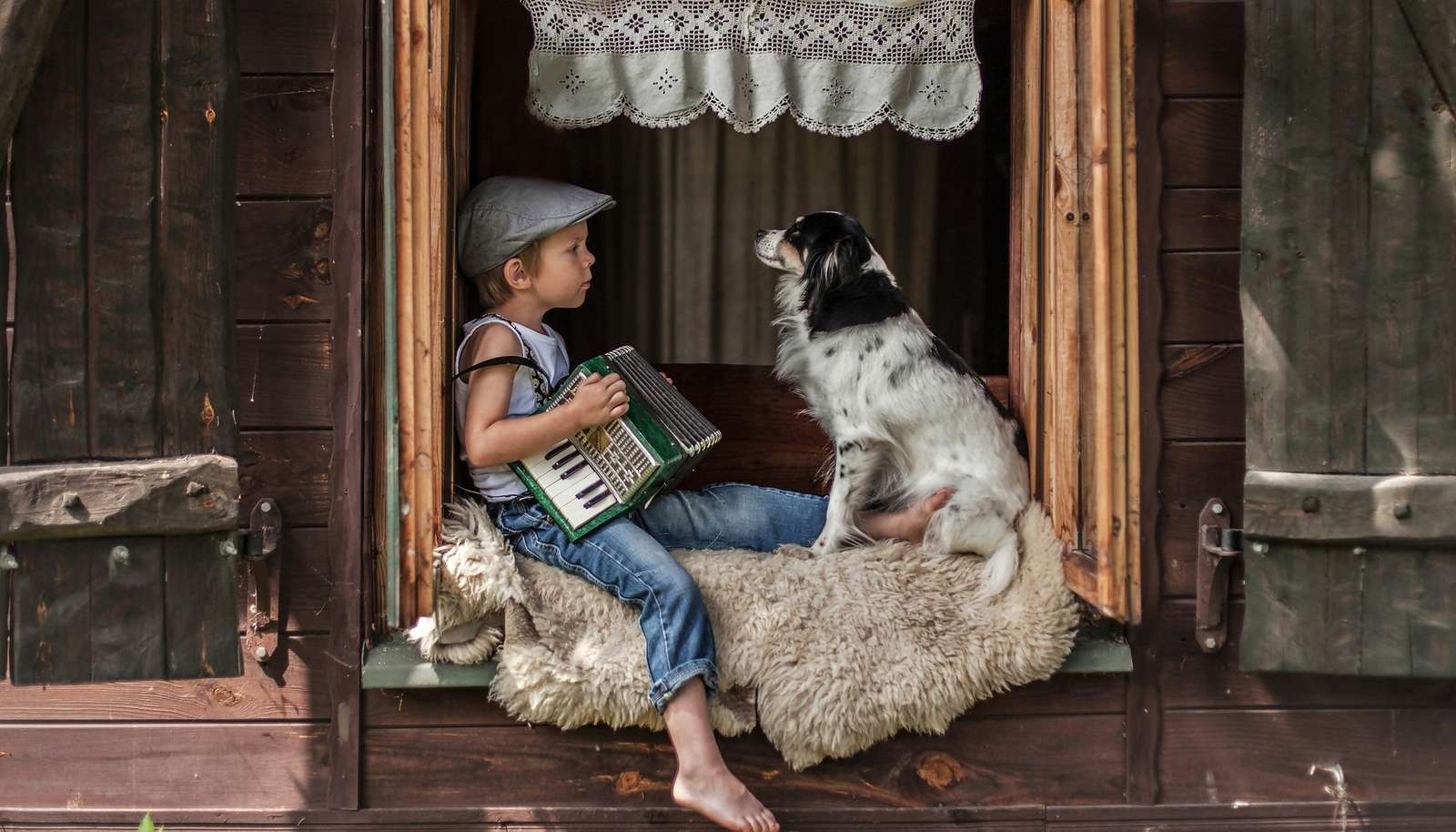Un niño tocando el acordeón en el campo con su perro. rompecabezas en línea