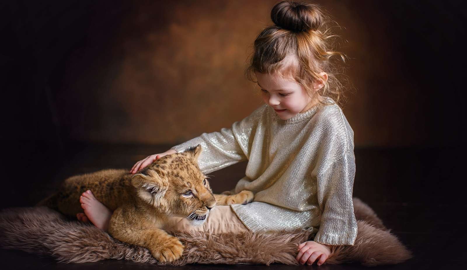 Una niña acaricia a un pequeño cachorro de león. rompecabezas en línea